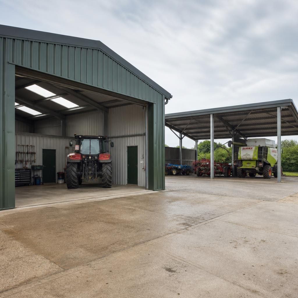 Steel-framed garage beside an open canopy sheltering agricultural machinery